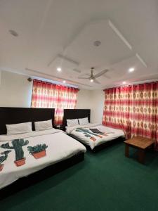 2 Betten in einem Zimmer mit roten Vorhängen in der Unterkunft Orophile Nest And Resturent in Skardu