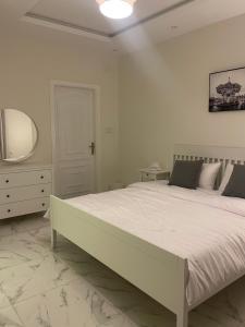 a white bedroom with a large bed and a mirror at شقة الردف in Taif
