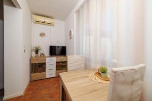 a dining room with a table and a television at Apartments Near the sea Barbat in Barbat na Rabu