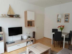 ein Wohnzimmer mit Flachbildfernseher und Tisch in der Unterkunft Zinnowitz Haus Zur Düne in Zinnowitz