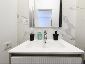 a white bathroom with a sink and a mirror at Aparthotel Madonna Residence Petunilor in Craiova +25 photos