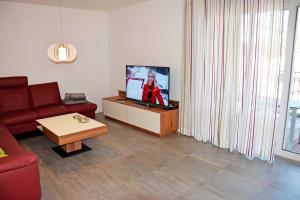 a living room with a red couch and a tv at Ferienappartement mit Balkon im Os in Binz +13 photos
