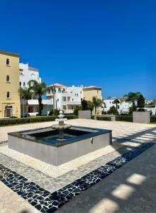 a fountain in a courtyard with buildings in the background at Asilah VIP - Sea view & Swimming Pools - Garage Private in Asilah