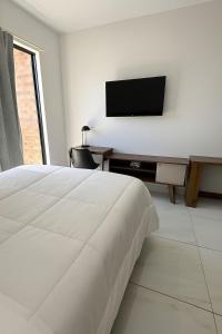 Un dormitorio blanco con una cama y un televisor de pantalla plana. en Flat Intermares, en Cabedelo