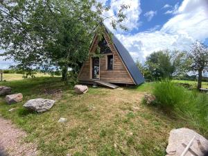 a small house with a gambrel roof on a field at l'insolite in Belmont