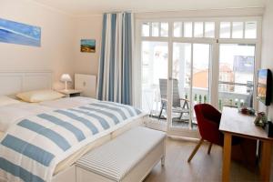a bedroom with a bed and a desk and a balcony at Fewo Rosenhof TW Queen in Kühlungsborn