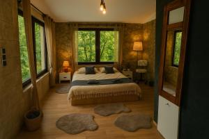 Un dormitorio con una cama y dos grandes ventanales. en Forest Hide Tiny House, en Covasna