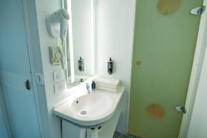 a white bathroom with a sink and a mirror at ibis budget Sète centre in Sète