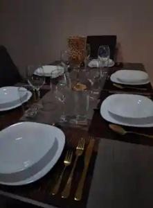 a wooden table with white plates and forks and glasses at Depa Santorini in Veracruz