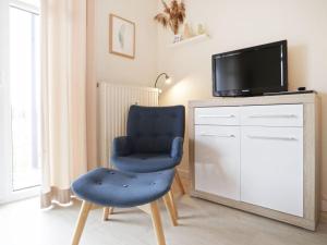 une chaise bleue assise devant une télévision dans l'établissement Residenz Haffblick, Wohnung 37, à Boltenhagen