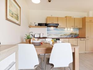 une cuisine avec une table et deux chaises blanches dans l'établissement Residenz Haffblick, Wohnung 37, à Boltenhagen