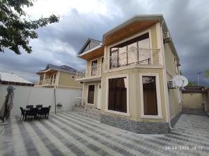 a house with a balcony and a table and chairs at Twin villas VSL in Gabala