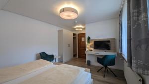 a bedroom with a bed and a desk and a television at Hochschwarzwald-Hof in Schluchsee