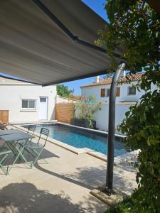 a patio with a swimming pool and a black umbrella at VILLA EN PROVENCE AVEC PISCINE AU CALME À ARLES - Camargue in Arles