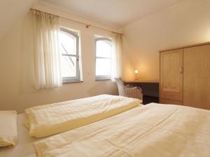 a bedroom with two beds and a cabinet and two windows at Meeresbrise Whg 6 in Tarnewitz