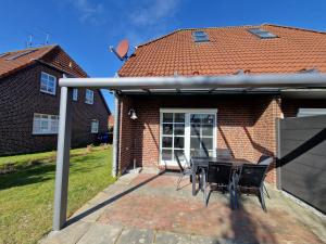 a patio with a table and chairs in front of a house at Nr 97 - Ferienhaus Uferstraße in Carolinensiel