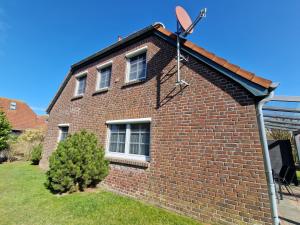 a red brick house with a satellite at Nr 97 - Ferienhaus Uferstraße in Carolinensiel