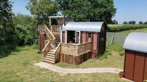 a house with a deck and stairs in a yard at Get Away Hide Away in East Dereham