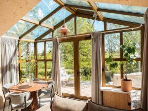 un salón acristalado con techo de cristal, mesa y sillas en Holiday Home in Friesland with Greenhouse Charm, en Scherpenzeel