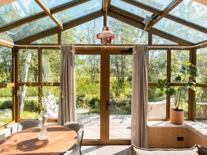 un salón acristalado con mesa de madera y sillas en Holiday Home in Friesland with Greenhouse Charm, en Scherpenzeel 25 fotos más