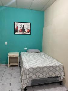 una cama en una habitación con una pared azul en Habitación las brisas, en El Rosario