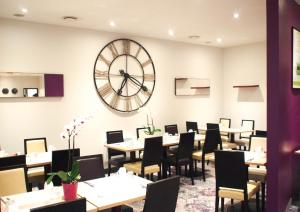 un restaurante con mesas y un reloj grande en la pared en Mercure Angers Centre Gare, en Angers