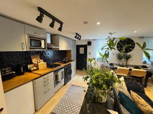 une cuisine avec des armoires blanches et une table avec des plantes dans l'établissement Cozy Cottage Coventry self check-in after 3pm, Pets Friendly, à Longford 8 autres photos