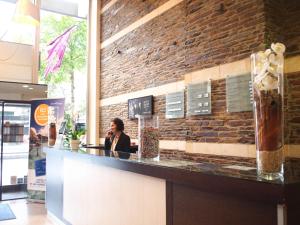 a woman sitting at a bar in a restaurant at Mercure Angers Centre Gare in Angers