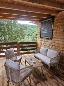 a porch with chairs and a couch and a table at Maison Bois in Grosseto-Prugna