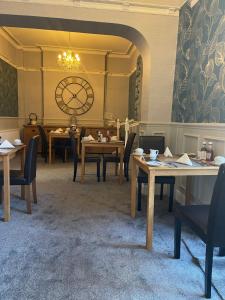 a room with tables and chairs and a clock on the wall at Milverton House in Llandudno