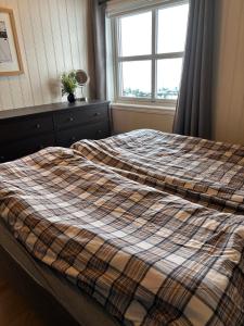 a bed with a plaid blanket on it in a bedroom at Apartment vårstølen - myrkdalen skisenter in Vossevangen