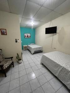 Un dormitorio con dos camas y un televisor de pantalla plana. en Habitación las brisas, en El Rosario