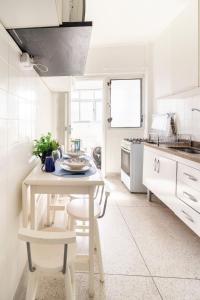 a white kitchen with a white table and chairs at Vista para o Mar & Pé na Areia in São Vicente