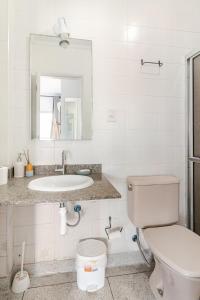 a white bathroom with a toilet and a sink at Vista para o Mar & Pé na Areia in São Vicente