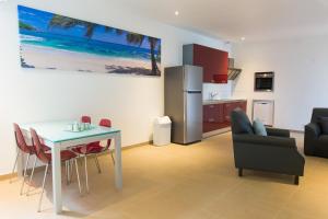 een keuken en een woonkamer met een tafel en een koelkast bij Bubali Luxury Apartments - Adults Only - Wheelchair Friendly in Palm-Eagle Beach