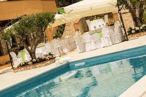 una piscina con sillas blancas, una mesa y una boda en Villa Giulia Del Cavaliere, en Castrovillari