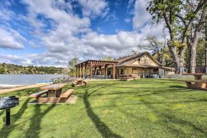 a building with picnic tables in the grass next to a lake at Hot Tub and Game Room Family Retreat in Groveland! in Groveland