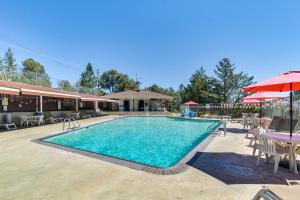 a swimming pool with tables and chairs and an umbrella at Hot Tub and Game Room Family Retreat in Groveland! in Groveland