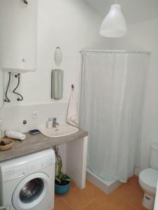 a bathroom with a washing machine and a sink at Casas do Montinho in Melides +27 photos
