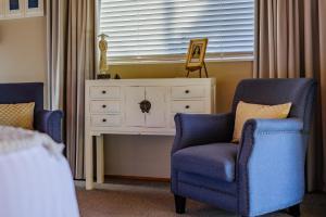 een slaapkamer met twee blauwe stoelen en een ladekast bij Harbour View Cottage Bay of Islands in Opua