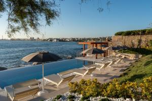 a row of chairs and umbrellas next to the water at Villa Giada Luxury Boutique Hotel in Civitavecchia