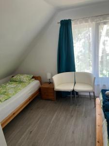 a bedroom with a bed and a chair and a window at Napsugár Vendégház Tokaj-Rakamaz in Rakamaz
