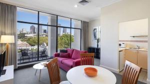 a living room with a purple couch and a table at Nesuto Woolloomooloo in Sydney