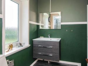 a green bathroom with a sink and a mirror at 4 star holiday home in Brønderslev in Brønderslev +30 photos