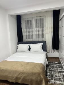 een slaapkamer met een groot wit bed met zwarte gordijnen bij Fushkosov in Kosovo Polje