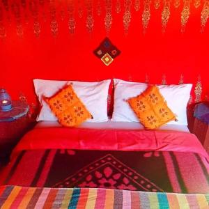 a red bedroom with a bed with orange pillows at Camp Desert Sky in Merzouga
