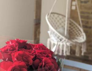 un mazzo di rose rosse in un vaso accanto a una sedia di Gîte Bohême a Donchery