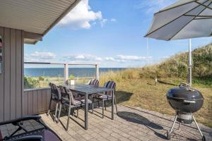 ein Grill sowie ein Tisch und Stühle auf einer Terrasse in der Unterkunft 755 Hvide Sande - Søndergade 106 in Hvide Sande