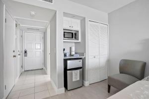 Turtle Dunes Ocean Front Studio Condo on Amelia Island Plantation في فرناندينا بيتش: مطبخ صغير باللون الأبيض مع كرسي وميكروويف