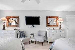 Turtle Dunes Ocean Front Studio Condo on Amelia Island Plantation في فرناندينا بيتش: غرفة نوم بسريرين وتلفزيون ومرايا